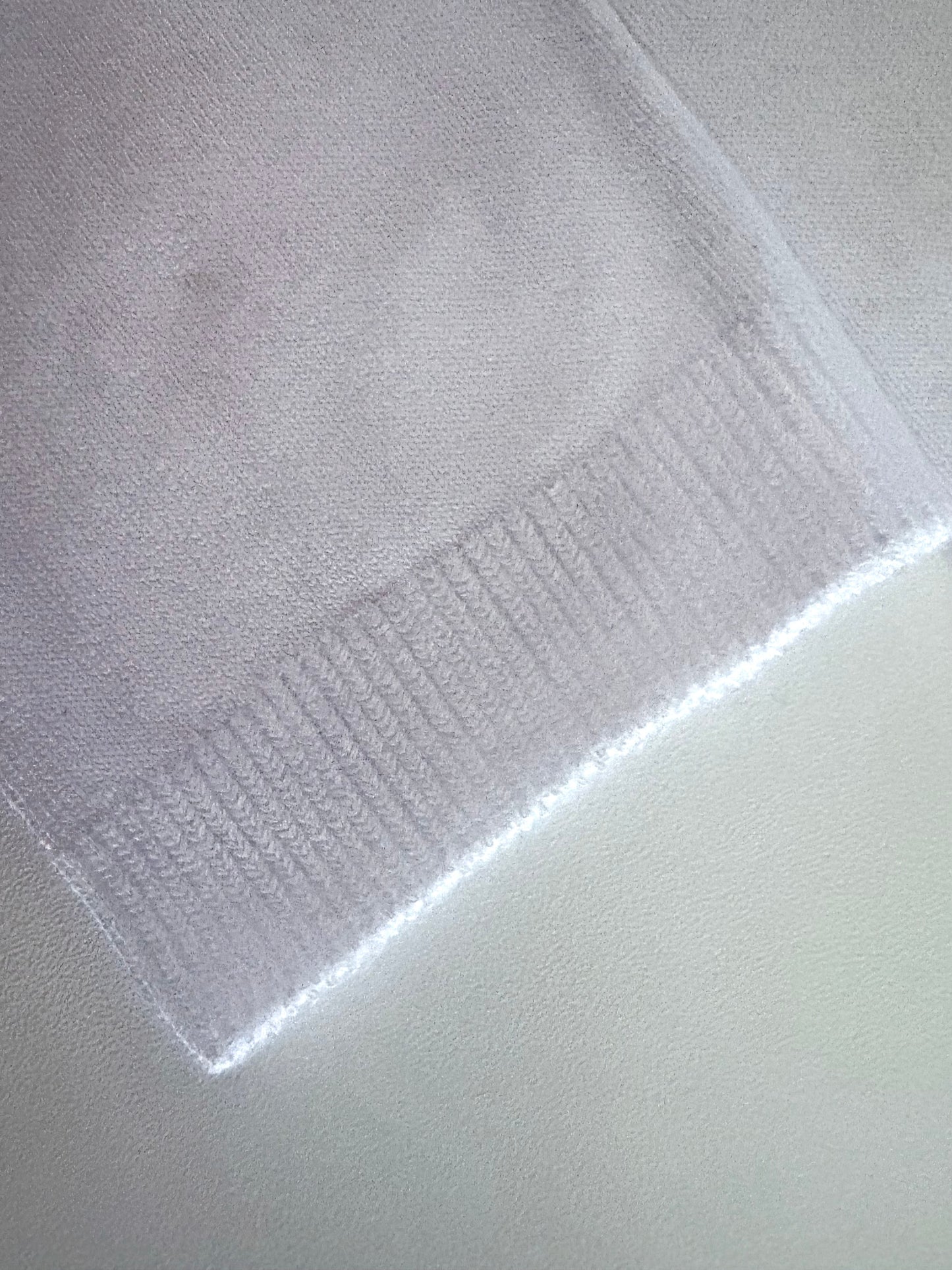 Close-up of a textured white fabric with a subtle pattern on a light gray background