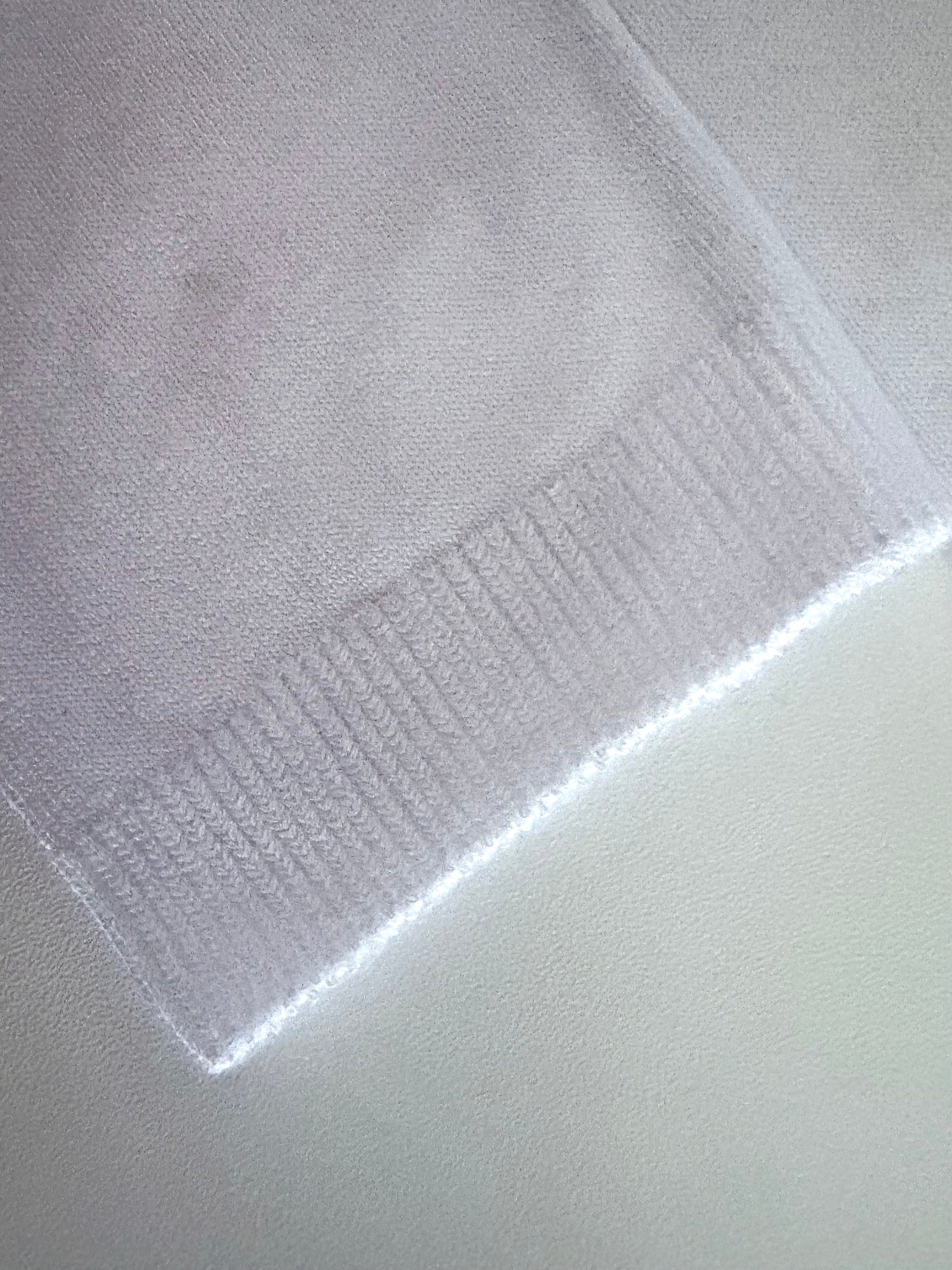 Close-up of a textured white fabric with a subtle pattern on a light gray background